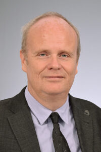 Porträtfoto von Prof. Matthias Schwab, der einen dunklen anug und eine dunkle Krawatte trägt